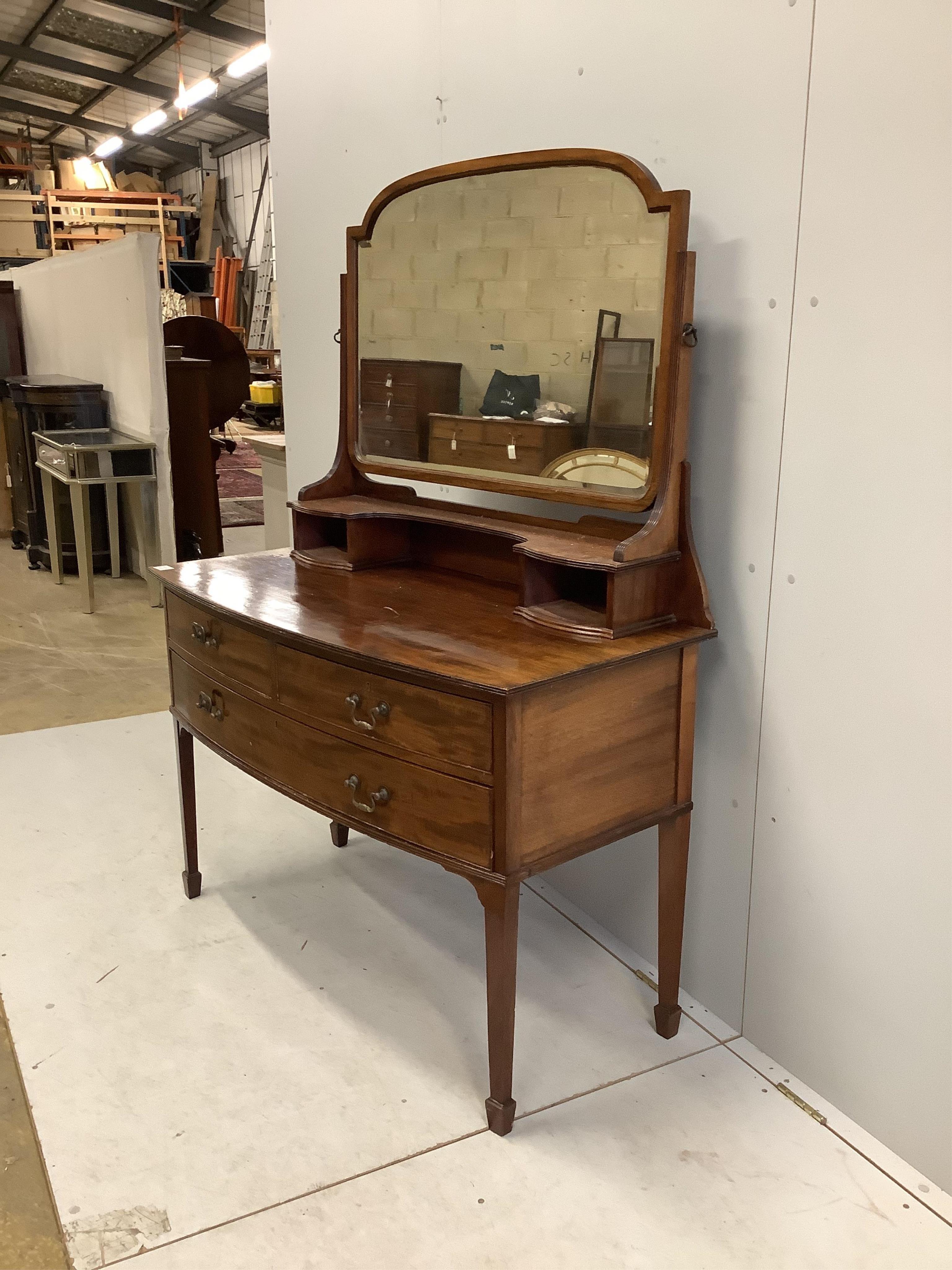 An early 20th century mahogany bowfront dressing table, fitted two short and one long drawer with brass loop handles and square tapered legs with spade feet, width 116cm, depth 57cm, height 156cm. Condition - fair